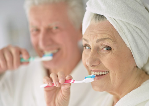 Importancia de la higiene dental en las personas mayores: Una mujer anciana se cepilla los dientes